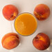 A glass of Endless Harvest peach juice next to peaches.