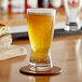 A glass of Endless Harvest peach fruit puree on a table next to a sandwich.