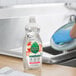 A person cleaning a dish in a kitchen sink with Seventh Generation dishwashing liquid.