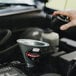 A person using a Behrens metal funnel to pour oil into a car engine.