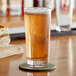 A glass of beer on a table with a sandwich.