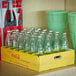 A wooden crate filled with green glass Coca-Cola bottles.