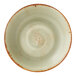 A round, green coupe bowl with a rustic, speckled design and a brown rim.