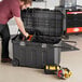 A man opening a Stanley black and yellow mobile tool chest to reveal tools inside.