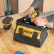 A person holding a yellow and black DeWalt drill kit bag.