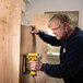 A man using a DeWalt 18 gauge finish stapler to attach a piece of wood.