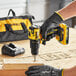 A person using a yellow and black DeWalt cordless drill to make a wooden box.