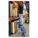 A man standing on a blue Vestil 4-step ladder in a warehouse.