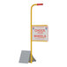 An aluminum wheel chock with a yellow and red sign and an ergonomic handle.