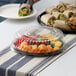 A Visions black plastic catering tray with a high dome lid holding fruit and a sandwich on a table outdoors.