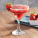 A glass of Island Oasis strawberry beverage with a strawberry garnish on the rim.