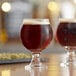 Two Libbey Belgian beer tasting glasses filled with beer on a table.