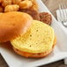 A breakfast sandwich with a Papetti's scrambled egg patty, cheese, and hash browns on a plate.