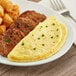 A white plate with an Abbotsford Farms Cheddar Cheese Omelet and sausage.