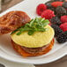 A plate with a breakfast sandwich made with an Abbotsford Farms scrambled egg patty and berries.