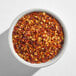 A white bowl filled with crushed red pepper flakes.