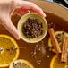 A person holding a bowl of cloves and spices.
