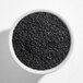 A white bowl filled with black sesame seeds.