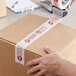 A person's hand using Tape Logic "Stop / Alto" tape to seal a box.