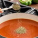 A person sprinkling Hometown Provisions Italian Seasoning into a pot of soup.