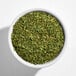 A white bowl filled with dried parsley flakes.