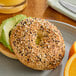 A plate with an everything bagel topped with avocado and oranges.