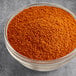 A bowl of orange Hometown Provisions Taco Seasoning on a gray surface.