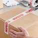 A person using Tape Logic "Inspected" carton sealer tape to seal a cardboard box.