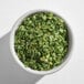 A white bowl filled with dried chive pieces.