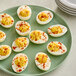 A plate of deviled eggs with paprika sprinkled on top.