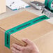 A hand using Tape Logic "Approved" carton sealer tape to tape a box.