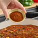 A person pouring Hometown Provisions chili powder into a bowl of food.