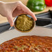 A person pouring Hometown Provisions ground cumin into a bowl of food.