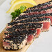 A piece of tuna with black sesame seeds on it.