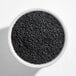 A white bowl filled with black sesame seeds.