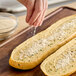 A person sprinkling garlic powder on a loaf of bread.
