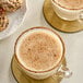 Two cups of coffee with a cinnamon rim and a plate of cookies on a white background.