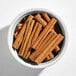 A white bowl filled with whole cinnamon sticks.