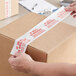 A person using Tape Logic carton sealing tape to seal a box.