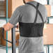 A man wearing a Lavex black back support belt standing next to a cart.