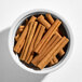 A white bowl filled with whole cinnamon sticks.