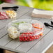 An Inline Plastics Essentials clear plastic 5-compartment round platter with a variety of food on it.