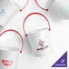 A group of white Howw Manufacturing plastic drink buckets with red handles.
