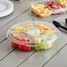 An Inline Plastics clear plastic 5-compartment tray with fruit in it on a table.