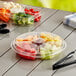 A clear plastic tray with 5 compartments of fruit and vegetables on a table.