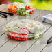 A clear Inline Plastics 5-compartment round platter with broccoli and other vegetables inside.