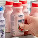 A person's hand holding a white bottle of Lifeway Low-Fat Strawberry Kefir.