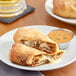 A plate with two pieces of Pizzeria Uno Steak and Cheese Calzone with sauce.