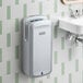 A silver automatic vertical hand dryer with HEPA filtration mounted on a bathroom wall.