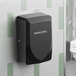 A black automatic hand dryer mounted on a tiled restroom wall.